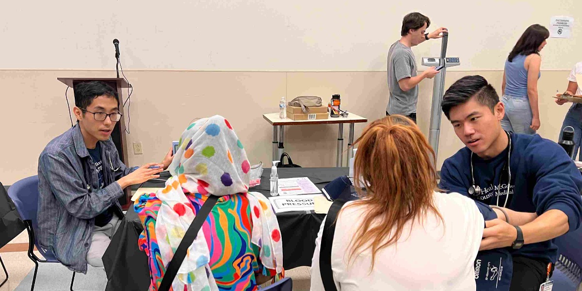 Student volunteers helping take the blood pressures and height of patients who attended for free health screenings at our Refugee and Immigrant Health Fair.